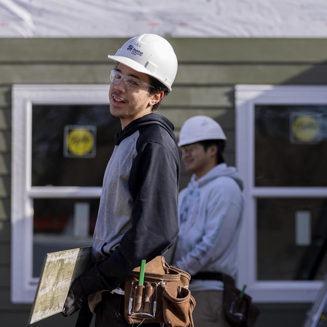  Students work at a construction site building a house